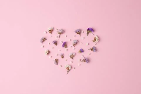 Minimal composition with a heart shape of flowers on pink background. Flat la Stock Photos