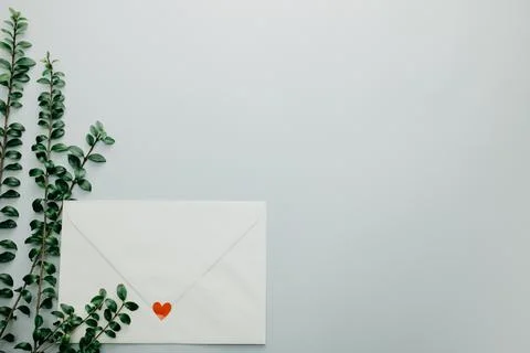 Minimal composition with a white envelope, heart and green leaves Stock Photos