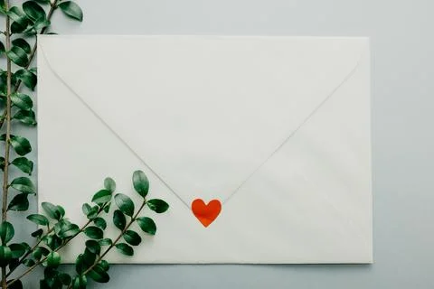 Minimal composition with a white envelope, heart and green leaves Stock Photos