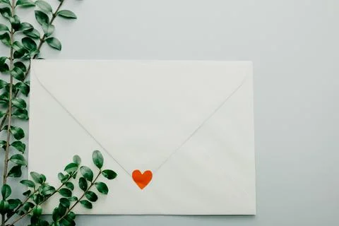 Minimal composition with a white envelope, heart and green leaves Stock Photos