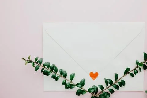 Minimal composition with a white envelope, heart and green leaves Stock Photos