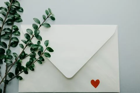Minimal composition with a white envelope, heart and green leaves Stock Photos