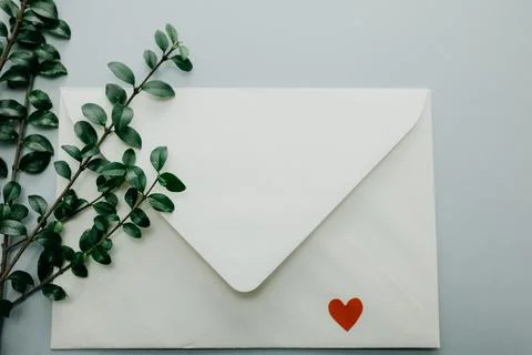 Minimal composition with a white envelope, heart and green leaves Stock Photos