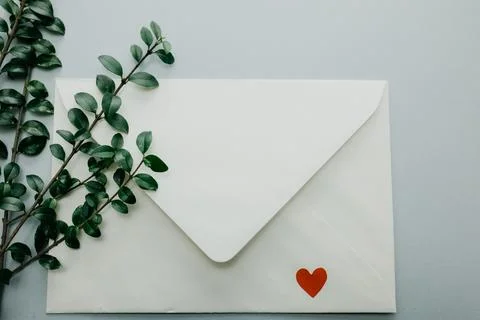 Minimal composition with a white envelope, heart and green leaves Stock Photos
