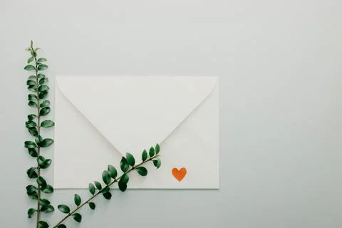 Minimal composition with a white envelope, heart and green leaves Stock Photos