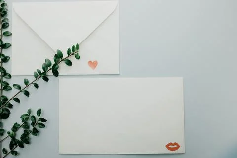 Minimal composition with a white envelope, heart and green leaves Stock Photos