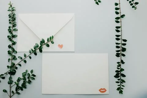 Minimal composition with a white envelope, heart and green leaves Stock Photos