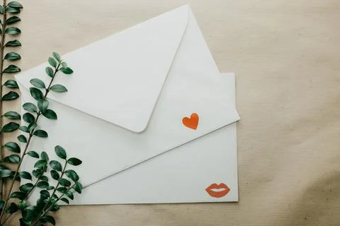 Minimal composition with a white envelope, heart and green leaves Stock Photos
