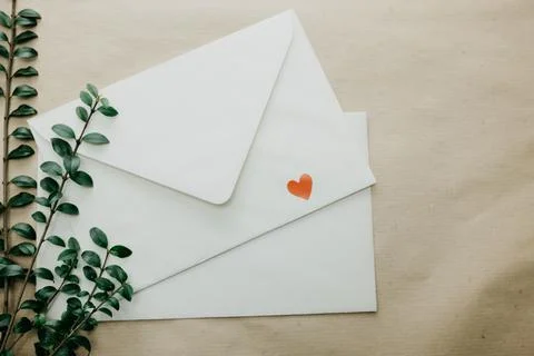 Minimal composition with a white envelope, heart and green leaves Stock Photos