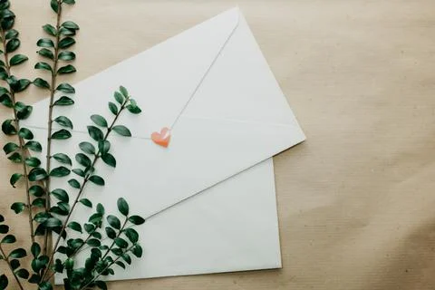 Minimal composition with a white envelope, heart and green leaves Stock Photos