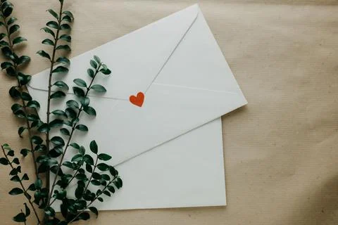 Minimal composition with a white envelope, heart and green leaves 写真素材