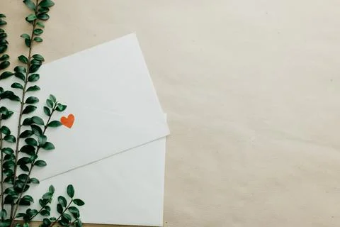 Minimal composition with a white envelope, heart and green leaves Stock Photos