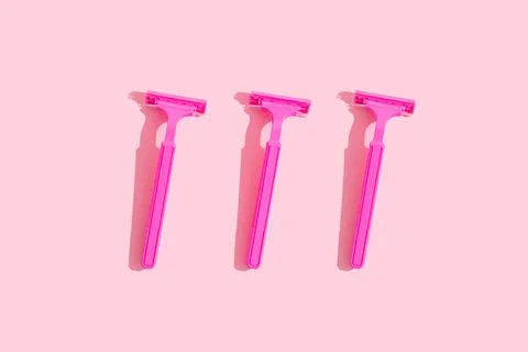 Minimal concept: three raspberry-colored ladies' razors with hard shades on a Stock Photos