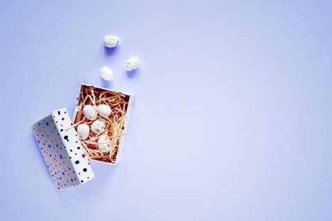 Minimal Easter background with Easter eggs in a gift box on blue background Stock Photos