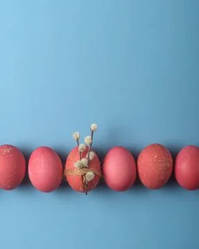 Minimal Easter border of red dyed eggs on blue background, center egg wrapped Stock Photos