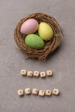 Minimal Easter concept. Nest with three colorful easter eggs with text Happy Stock Photos