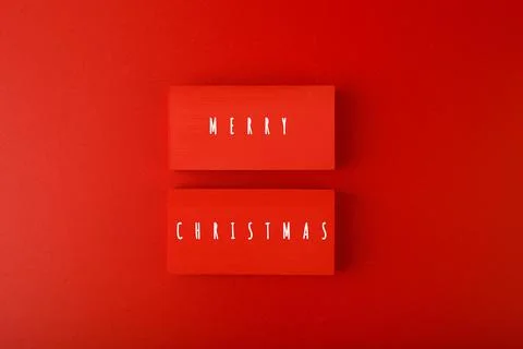 Minimal flat lay Christmas theme. Merry Christmas written on two red tablets Stock Photos