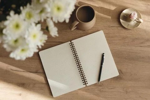 Minimal flat lay of an open grid notebook, coffee cup and chrysanthemum bou.. Foto stock