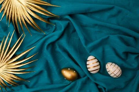 Minimal flat lay view of Easter eggs and golden palm leaves against blue Foto stock