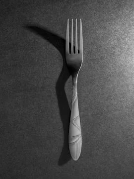 Minimal fork with dramatic shadow on textured surface Foto stock