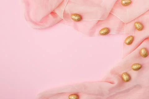 Minimal layout golden Easter eggs on a pink fabric background with copy space Stock Photos