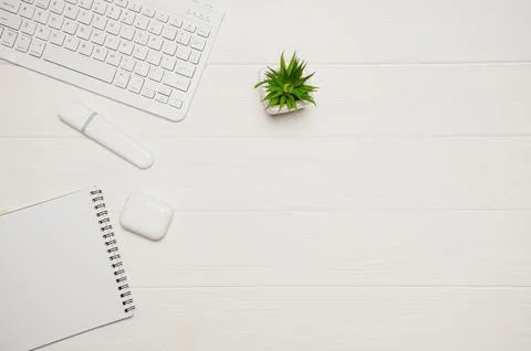 Minimal office desk setup for remote work showing a white keyboard, plant, ma Stock Photos