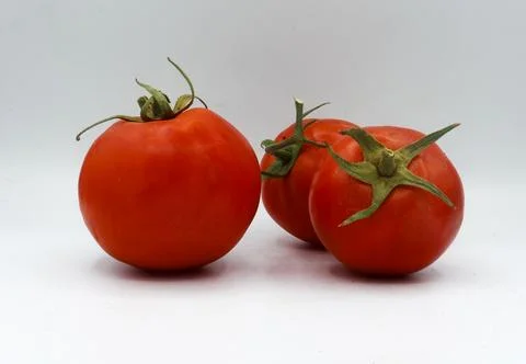 Minimal side-by-side placement of two ripe tomatoes on a white surface. Stock Photos