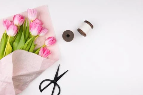 Minimal styled flat lay with pink tulips flowers, thread and scissors. Stock Photos