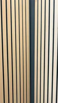 Minimalist background showing two sections of light oak wood slats on dark .. Stock Photos