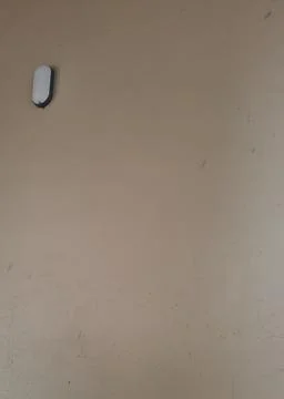 Minimalist Beige Wall with Single Wall-Mounted Light Fixture 스톡 사진