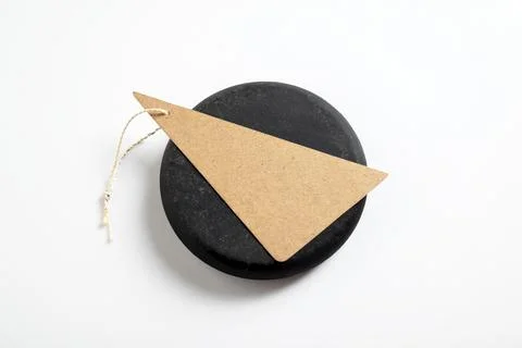 Minimalist black solid soap or stone with a blank triangular kraft paper ta.. Stock Photos