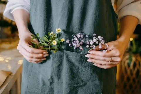 Minimalist capture of hands gently displaying small flowers and foliage in an Stock Photos