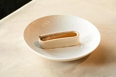 Minimalist chocolate eclair dessert on white plate Stock Photos