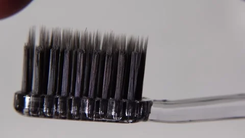 Minimalist close-up of a black toothbrush placed on a clean white background Stock Footage 313988275