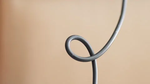 Minimalist close up of a looped black electronic cable Stock Footage 341990626