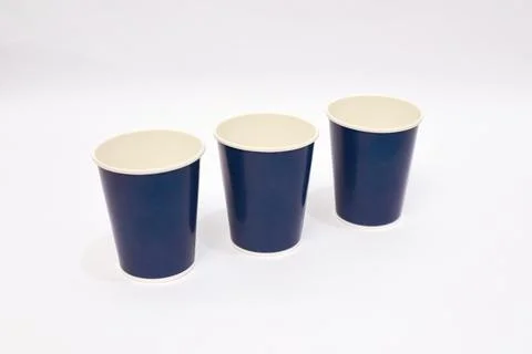 Minimalist composition featuring three navy blue paper cups on a pristine w.. Stock Photos