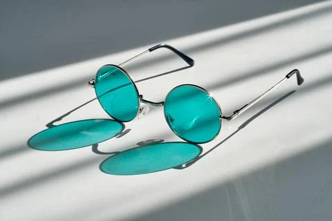 A minimalist composition featuring vintage thin metal frame sunglasses. Harsh Stock Photos
