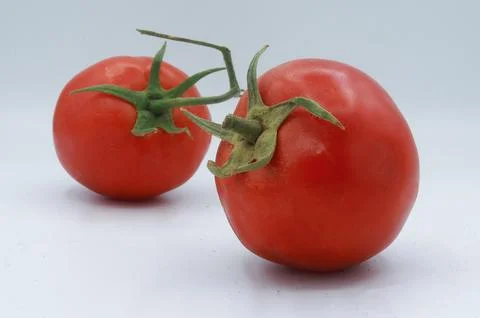 Minimalist composition of two ripe red tomatoes with green stems, placed Stock Photos