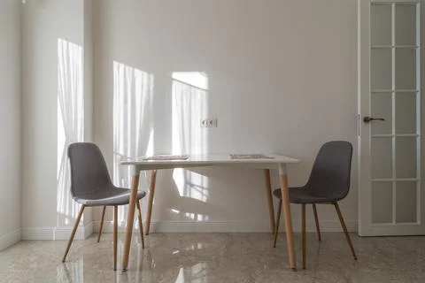 Minimalist dining area with white table and gray chairs 库存照片