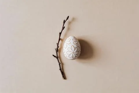 Minimalist Easter egg with floral pattern and bare branch on a neutral back.. Stock Photos