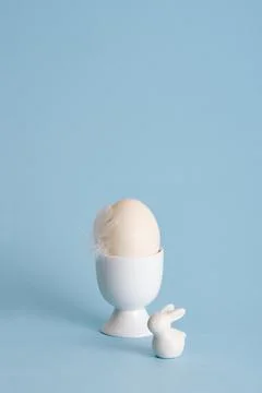 Minimalist Easter egg with a white feather bird and ceramic bunny on a past.. Stock Photos