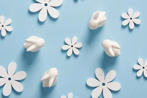 Minimalist Easter pattern with white bunnies and flowers on blue background. Stock Photos