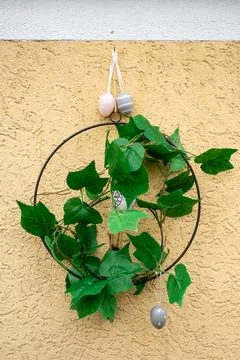 Minimalist Easter Wreath with Decorative Eggs on Yellow Wall Foto stock