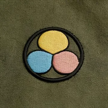 A minimalist embroidered patch in a circular form with three colorful petal.. Stock Photos