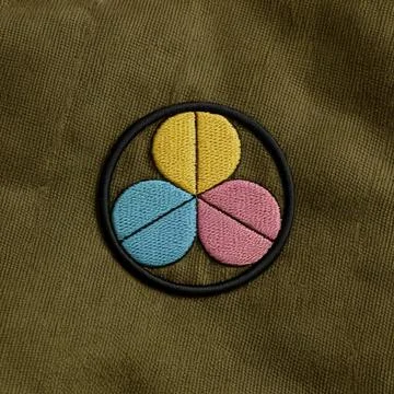 A minimalist embroidered patch in a circular form with three colorful petal.. Stock Photos