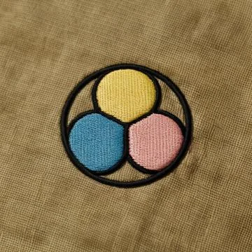 A minimalist embroidered patch in a circular form with three colorful petal.. Stock Photos