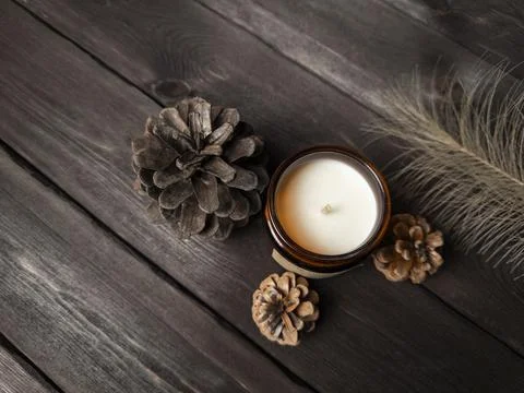 A minimalist flat lay featuring a brown glass candle, pine cones Stock Photos