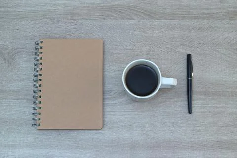 Minimalist flat lay with kraft notebook, coffee cup, and pen on wooden back.. Stock Photos