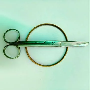 Minimalist flat lay of metal scissors and circular brass ring cutting tool backg Stock Photos