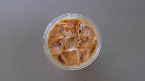 Minimalist flat lay top view of a refreshing iced latte coffee with ice cub.. Vídeos de archivo 348284517